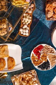 top view of Kazakhstani treats. An assortment of pastries, cookies, and nuts arranged on a blue velvet tablecloth. Perfect for a party or special occasion.