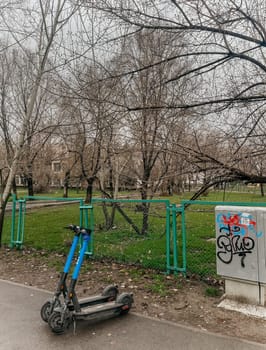 two blue electric scooters in autumn on the street near the park.