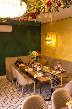 Elegantly decorated restaurant interior with long table set for special event. White tablecloth, flowers, candles, chandelier.