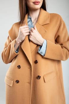 Caucasian female model posing in a stylish brown coat against a white background. Fashion, style, elegance, and beauty concept.