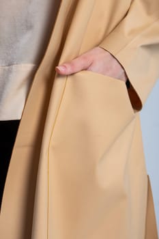 A model wearing an elegant beige coat with large front pockets. The coat is perfect for staying warm and stylish in the fall and winter.