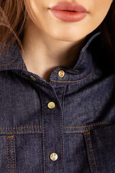 A young woman in a blue denim shirt dress with a collar and long sleeves. Fitted at the waist with a stretchy waistband.