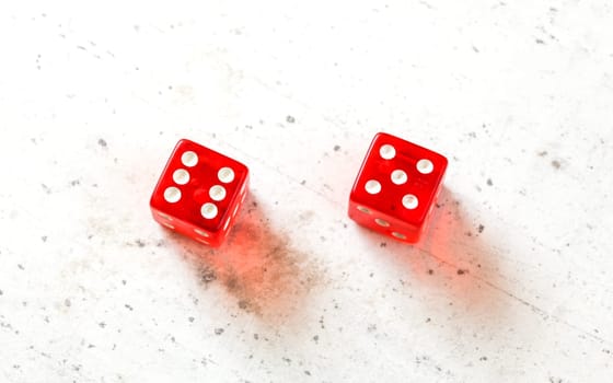 Two red craps dices showing Yo-leven	 (number 6 and 5) overhead shot on white board