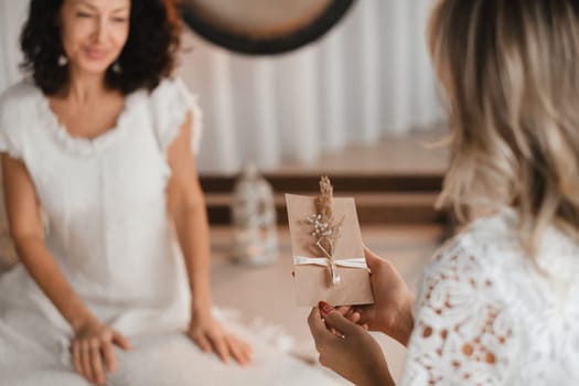 A woman in white clothes holds an envelope with a wish in her hands. The concept of a women's circle.