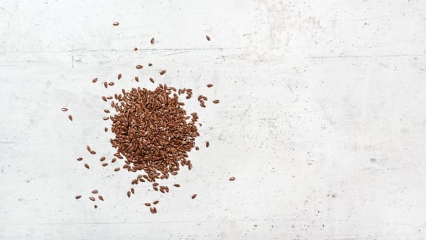 Flax seeds on white stone like board, view from above, banner with space for text right side