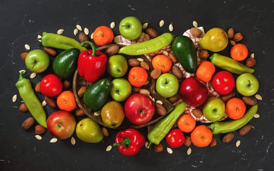 Mixed fruit and vegetables with some nuts on black board, view from above