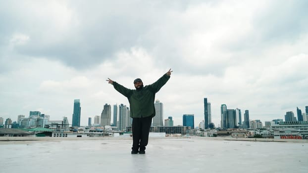 Motion shot of B-boy dance performance by professional street dancer at rooftop with sky scrapper, city view. Attractive asian hipster show energetic footstep. Outdoor sport 2024. Endeavor.