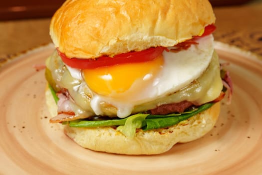Gourmet burger featuring a juicy beef patty topped with egg, crispy bacon.