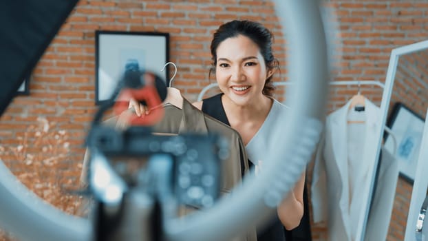 Woman influencer shoot live streaming vlog video review clothes social media or blog. Happy young girl with apparel vivancy studio lighting for marketing recording session broadcasting online.