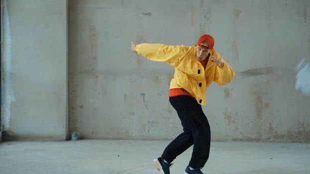 Caucasian hipster shows or practicing footstep at street, urban city. Motion shot of young stylish break dancer moving and stretch arm and leg. Outdoor sport 2024. Gray background. Endeavor.