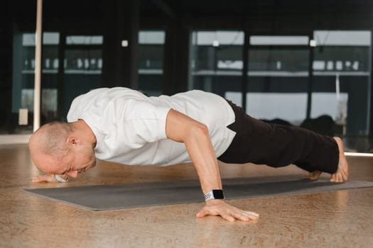 An athletic young man does exercises in the fitness room. A professional guy does yoga in the gym.