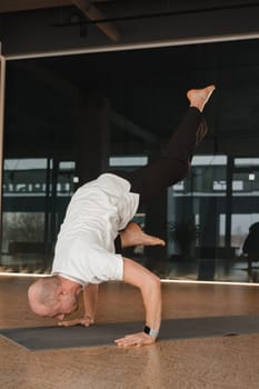 An athletic young man does exercises in the fitness room. A professional guy does yoga in the gym.