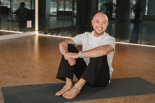 An athletic young man does exercises in the fitness room. A professional guy does yoga in the gym.