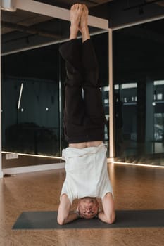 An athletic young man does exercises in the fitness room. A professional guy does yoga in the gym.