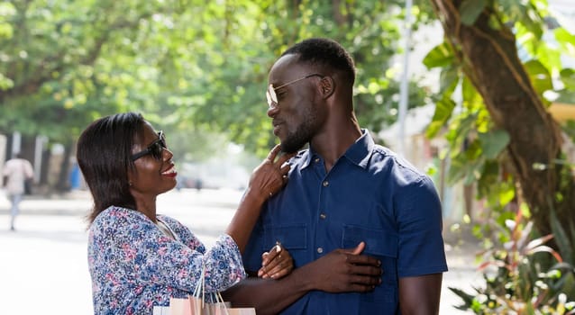 young woman standing outdoors cuddling her boyfriend smiling after shopping.