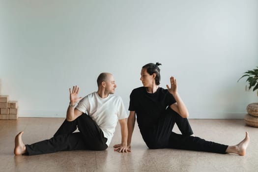 two young athletes practice yoga in the gym. Joint training, indoors, studio. The concept of a healthy lifestyle.