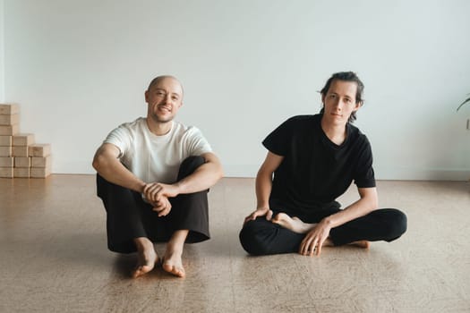 two young athletes practice yoga in the gym. Joint training, indoors, studio. The concept of a healthy lifestyle.