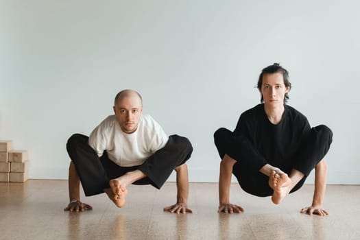 two young athletes practice yoga in the gym. Joint training, indoors, studio. The concept of a healthy lifestyle.