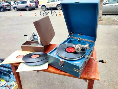 An old retro record playing on old vintage gramophone at flea market. Work of portable gramophone. Old vintage shabby record player, phonograph, potefone. Needle. Nostalgia antique audio turntable