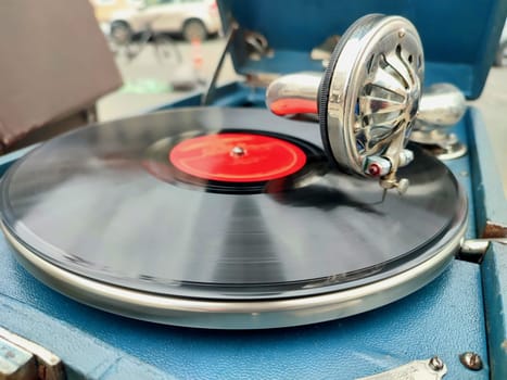 An old retro record playing on old vintage gramophone at flea market. Work of portable gramophone. Old vintage shabby record player, phonograph, potefone. Needle close up. Nostalgia antique turntable