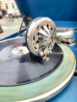 An old retro record playing on old vintage gramophone at flea market. Work of portable gramophone. Old vintage shabby record player, phonograph, potefone. Needle close up. Nostalgia antique turntable