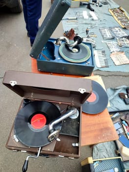 An old retro record playing on old vintage gramophone at flea market. Work of portable gramophone. Old vintage shabby record player, phonograph, potefone. Needle. Nostalgia antique audio turntable