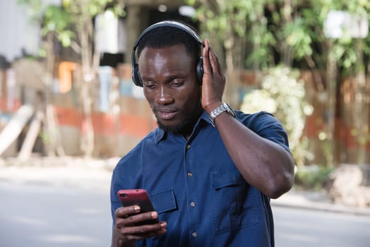 Man listens to music with headphones using a mobile phone outdoors.