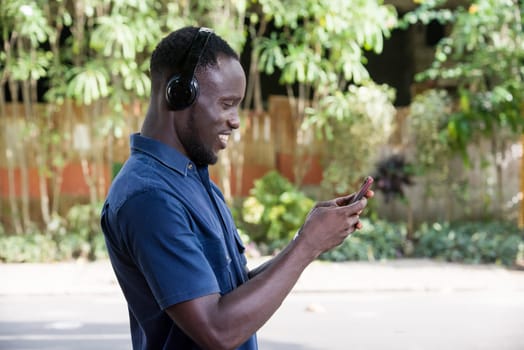 Man listens to music with headphones using a mobile phone outdoors.