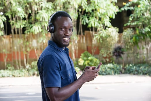 Man listens to music with headphones using a mobile phone outdoors.