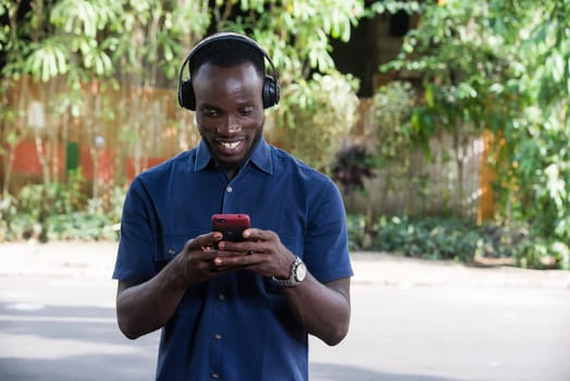 Man listens to music with headphones using a mobile phone outdoors.