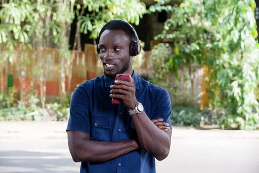 Young man standing outdoors looking at profile in profile smiling with mobile phone while smiling.