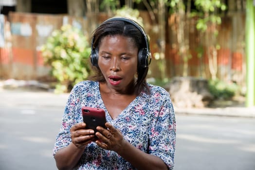 young woman standing outdoors looking at cell phone surprise.