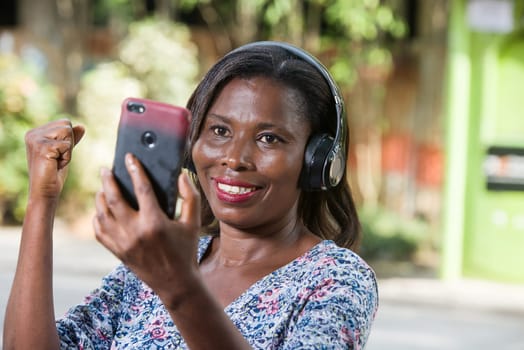 young woman standing outdoors looking at mobile phone laughing.