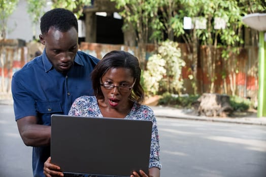 young couple outdoors looking at laptop.