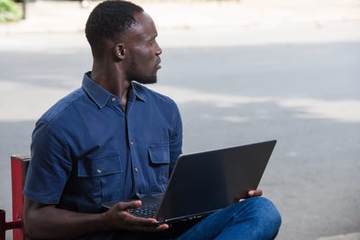 young man sitting outdoors with laptop watching something surprised.