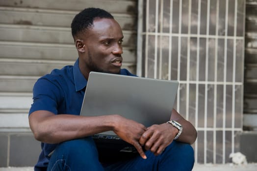 young man sitting on the floor with laptop looking in profile.