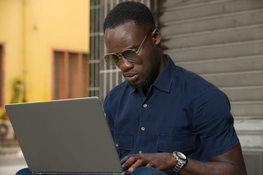 young man sitting outside looking at laptop.