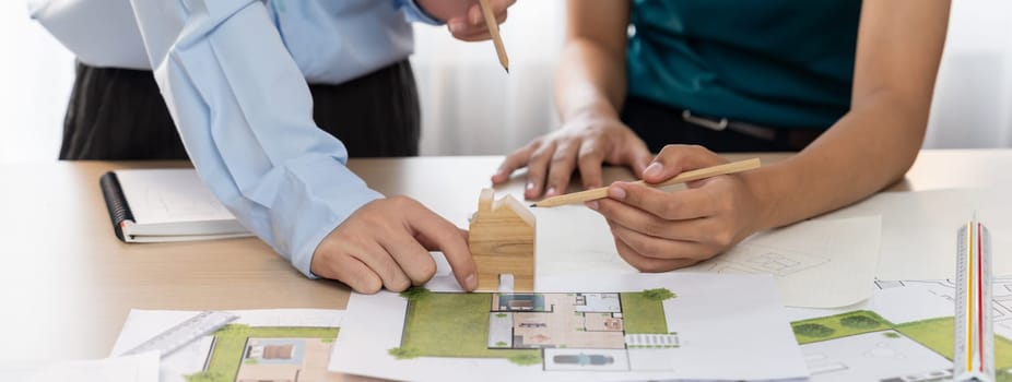 Professional architect team plans to build eco house at meeting table with green design document and architectural equipment scatter around. Living and design concept. Closeup. Delineation.