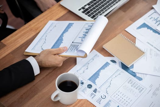 Diverse group of business analyst team analyzing financial data report paper on office table. Chart and graph dashboard by business intelligence analysis for strategic marketing planning Meticulous