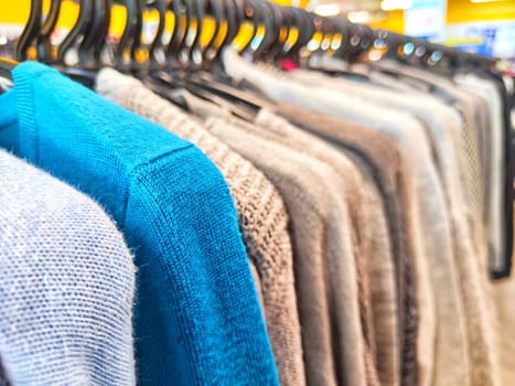 Colorful Assortment of Knitted Sweaters on Display in Bright Clothing Store. Variety of colorful sweaters hanging on a rack in a shop