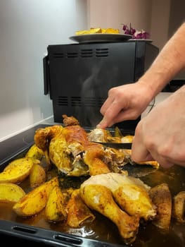 Hands cut baked chicken with potatoes with a knife. High quality photo