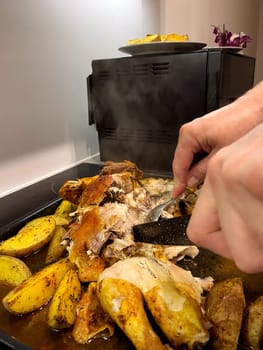 Hands cut baked chicken with potatoes with a knife. High quality photo