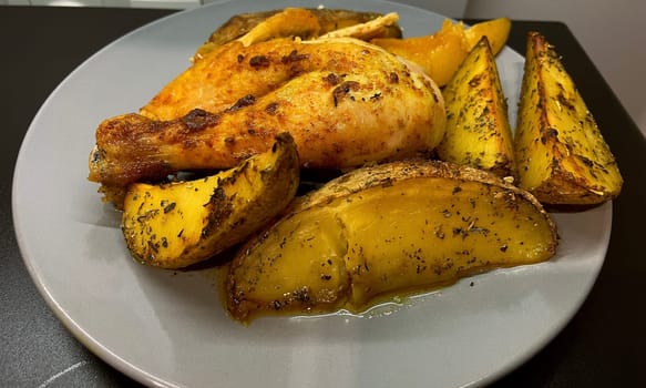 Baked potatoes and chicken in curry sauce on a gray plate. High quality photo