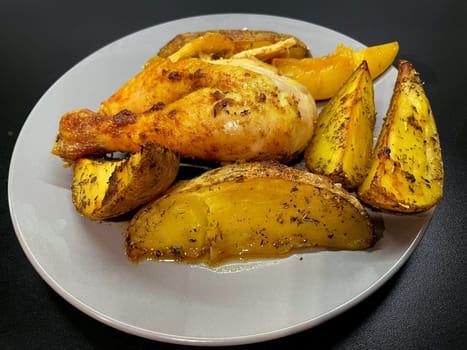 Baked potatoes and chicken in curry sauce on a gray plate. High quality photo