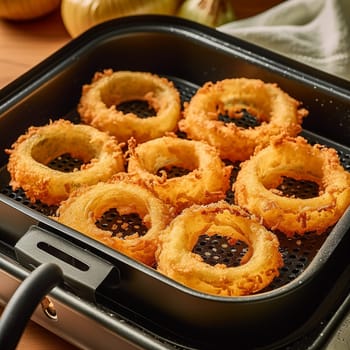 Golden-brown fried onion rings served in a black tray.