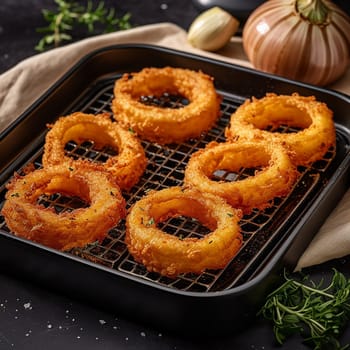 Crispy golden onion rings sprinkled with herbs on a wire rack.