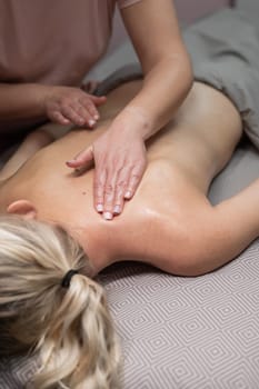 A woman undergoing a massage of the cervical-collar area. Vertical photo