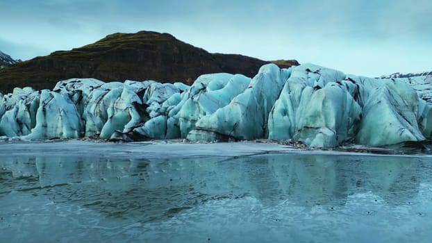 Aerial view of massive glaciers ice with crevasses, vatnajokull glacier and lagoon with frozen water in iceland. Diamond blue ice blocks floating on scandinavian lake. Slow motion.