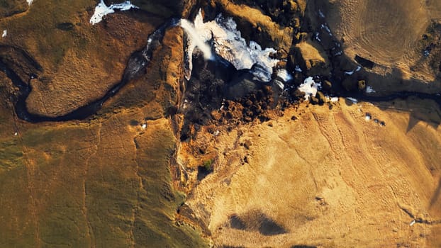 Nordic waterfall running down hills, foss a sidu cascade with river stream falling off of cliff in icelandic natural scenery. Beautiful water flow in arctic nature and wilderness. Drone shot.