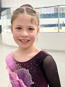 Poised at the entrance to the ice, this young athlete exudes excitement and readiness, clad in a sparkling competition dress, awaiting her moment to shine